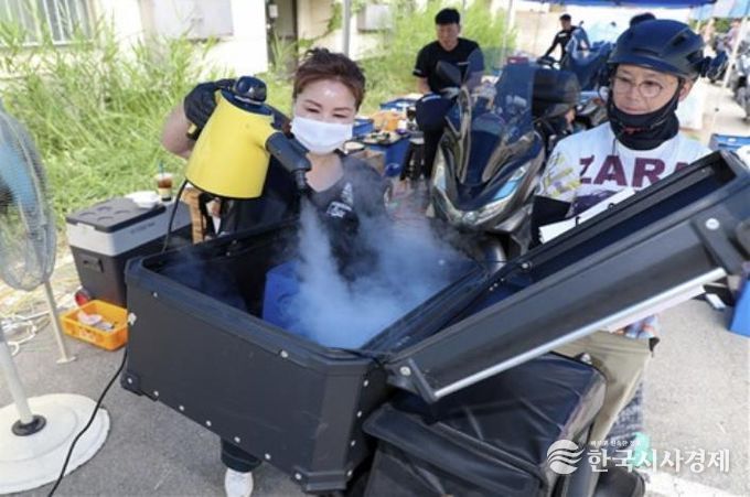 상반기 배달이륜차 무상 안전점검 행사에서 배달통 소독 서비스를 제공하고 있다