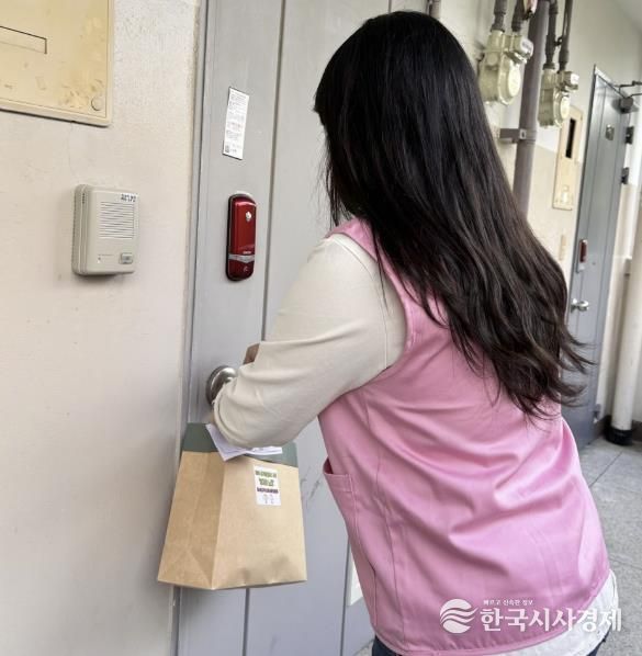 창4동지역사회보장협의체 위원이 복지사각지대 의심 가구에 식료품 꾸러미를 걸어놓고 있다.