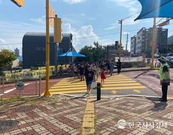 등하굣길 안전지킴이의 교통안내 지도에 따라 학생들이 안전하게 하교하고 있다.