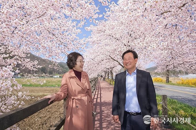 왼쪽 박의용 북면장, 오른쪽 진수곤 천안위례벚꽃축제추진위원장이 만개한 벚꽃나무 아래에서 축제 준비를 점검하며 환하게 웃고 있다.